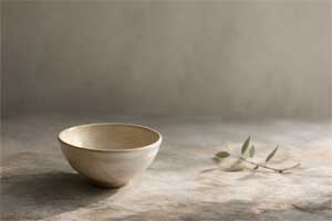 Recipiente sencillo sobre madera natural, reflejando la estética wabi-sabi y la calma