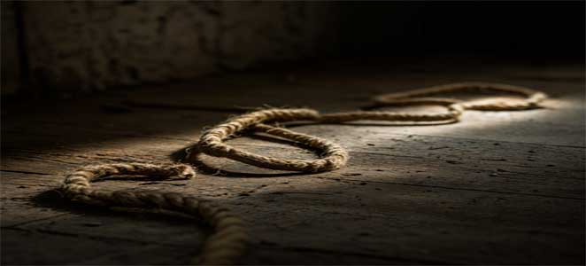 Una cuerda enrollada en el suelo bajo una luz tenue, sugiriendo la forma de una serpiente