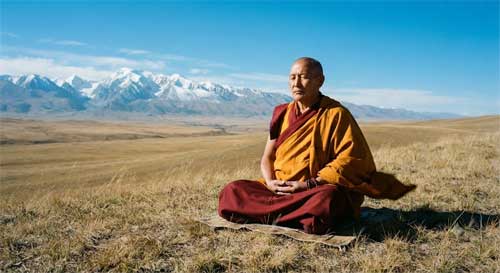 Monje meditativo en un paisaje de estepa abierta con montañas al fondo