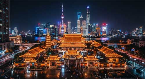 Templo Jing'an iluminado de noche con rascacielos de fondo