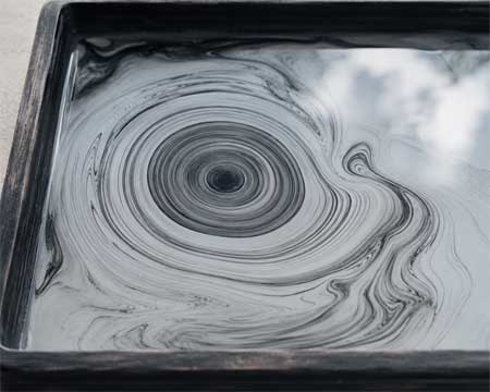Patrones circulares de tinta negra flotando sobre agua