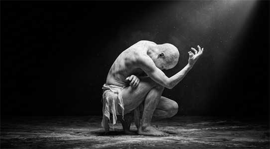 Bailarín de Butō cubierto de polvo blanco en un espacio oscuro y minimalista