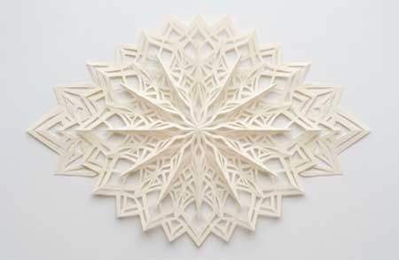 Diseño geométrico de Kirigami en papel blanco, mostrando cortes y pliegues simétricos