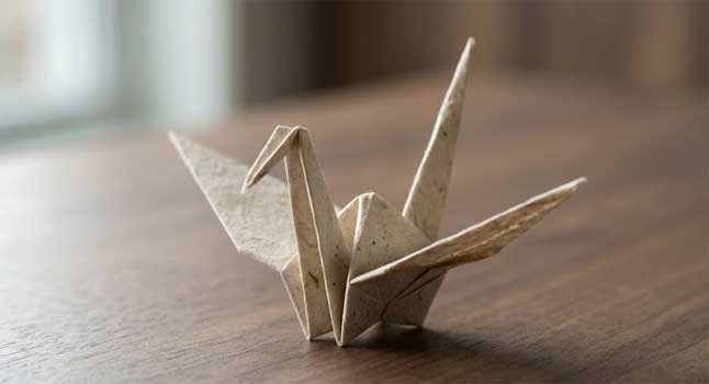 Grulla de origami hecha con papel washi texturizado, iluminación suave