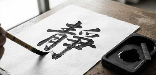 Pincel de caligrafía japonesa sobre papel Washi blanco, trazando un carácter con tinta negra intensa