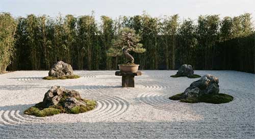 Jardín zen minimalista diseñado por Shunmyo Masuno con rocas estratégicamente posicionadas, arena rastrillada en patrones ondulantes, bonsái solitario como elemento focal meditativo